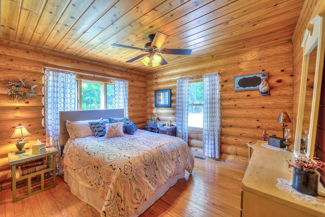 bedroom featuring ceiling fan, wooden ceiling, rustic walls, and light hardwood / wood-style flooring