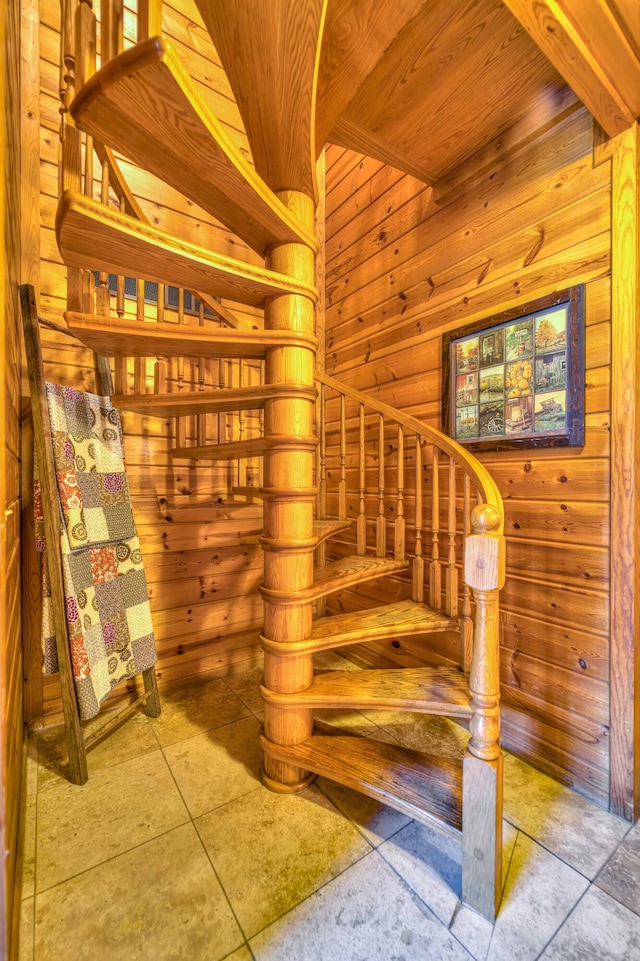 stairs featuring tile patterned flooring, wooden walls, and wooden ceiling