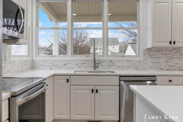 kitchen with tasteful backsplash, white cabinetry, sink, and appliances with stainless steel finishes