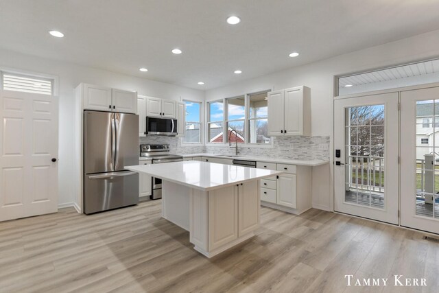 kitchen featuring white cabinetry, a kitchen island, stainless steel appliances, and light hardwood / wood-style floors