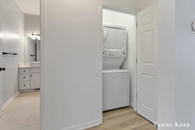 washroom featuring light wood-type flooring, sink, and stacked washer and clothes dryer