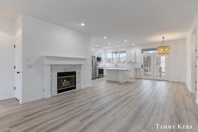 unfurnished living room featuring a fireplace, light wood-type flooring, french doors, and sink