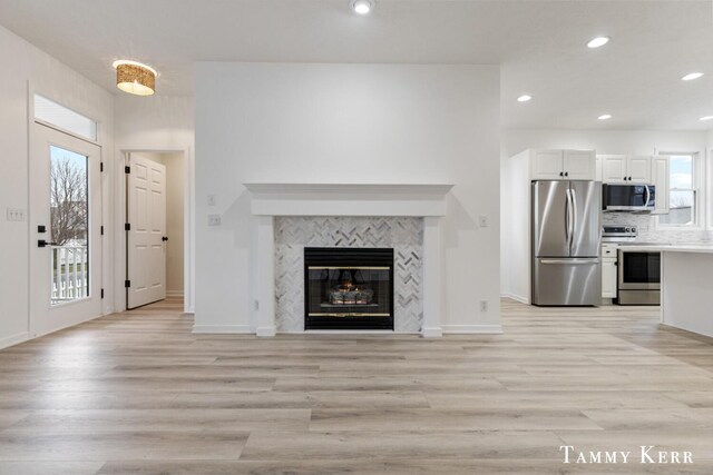 unfurnished living room featuring a tile fireplace and light wood-type flooring