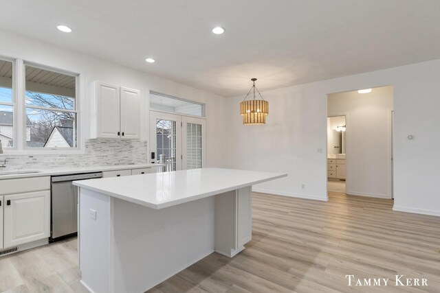 kitchen with pendant lighting, a center island, backsplash, white cabinets, and stainless steel dishwasher