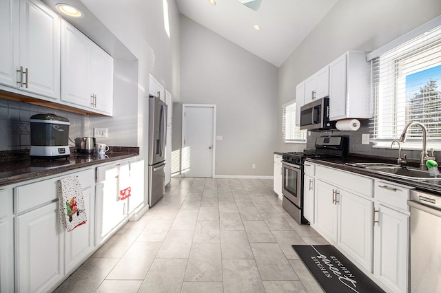 kitchen featuring high vaulted ceiling, stainless steel appliances, white cabinetry, and sink