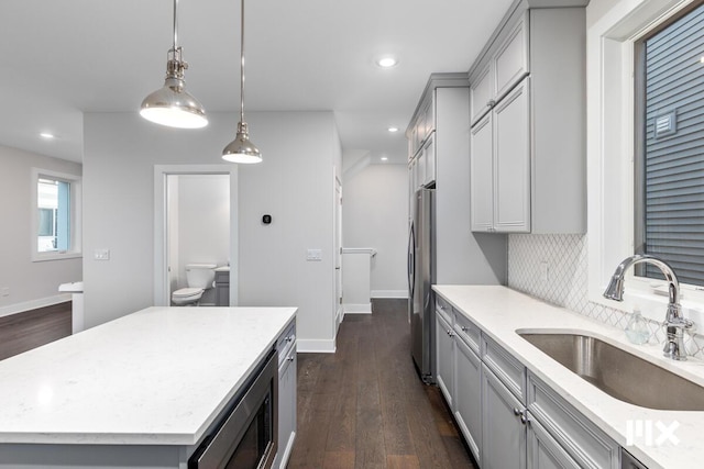 631 Fairview Ave NE Unit 2, Grand Rapids, MI 49503 - kitchen with light stone counters, gray cabinetry, dark wood-type flooring, a sink, and appliances with stainless steel finishes