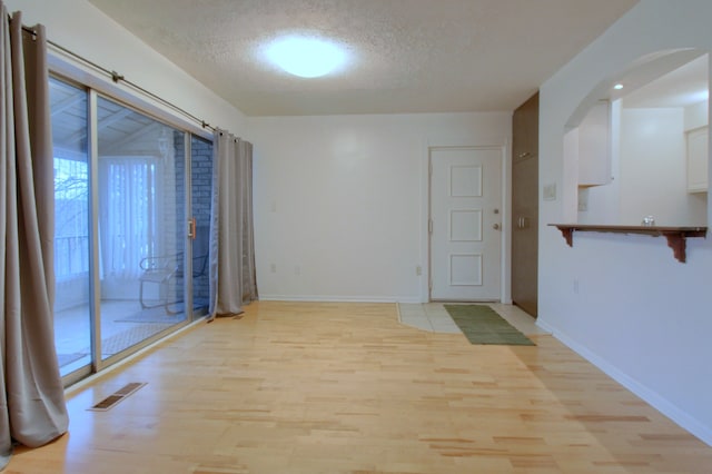 empty room with light hardwood / wood-style floors and a textured ceiling