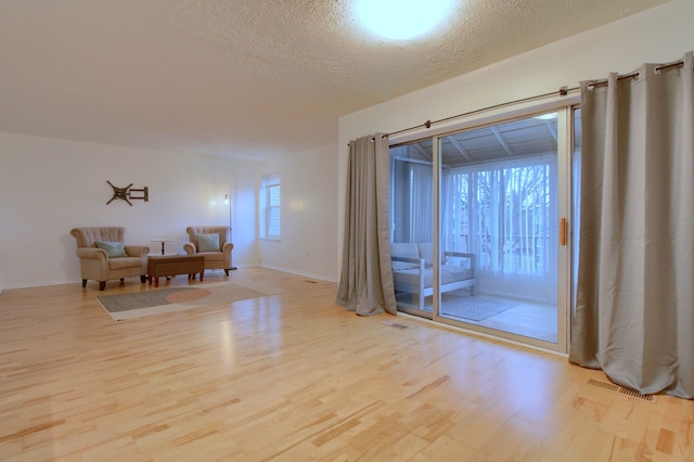 empty room with light hardwood / wood-style floors and a textured ceiling