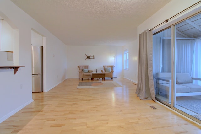 hall featuring a textured ceiling and light hardwood / wood-style floors