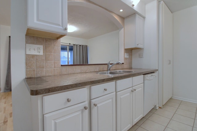 kitchen with decorative backsplash, white dishwasher, white cabinetry, and sink