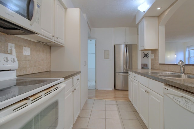 kitchen featuring backsplash, sink, white cabinets, and white appliances