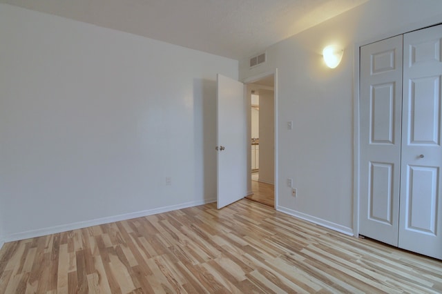 unfurnished bedroom with a textured ceiling, light hardwood / wood-style flooring, and a closet