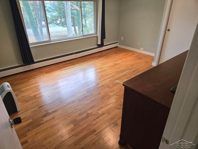 empty room featuring light hardwood / wood-style floors and a baseboard radiator