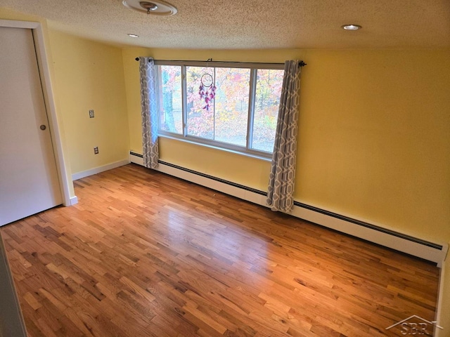 unfurnished room with a textured ceiling, light hardwood / wood-style floors, and a baseboard radiator