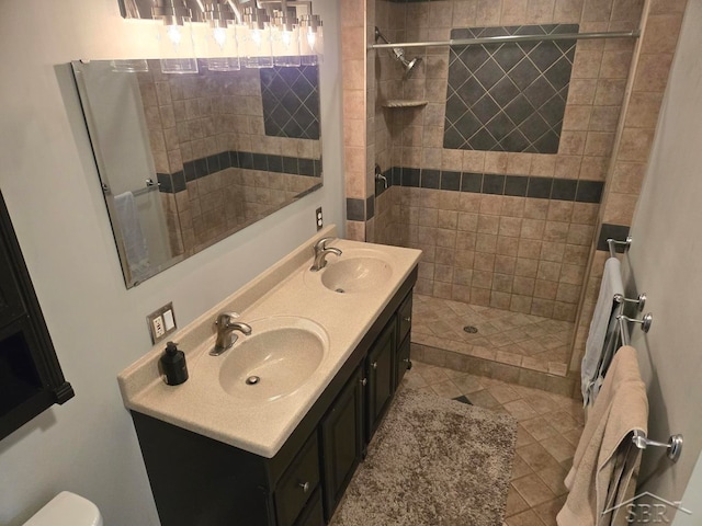 bathroom with a tile shower, vanity, and tile patterned floors