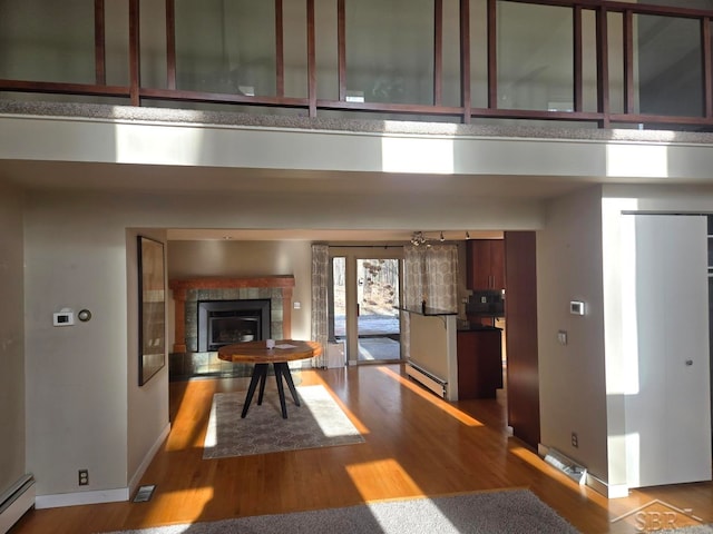 hallway featuring baseboard heating, hardwood / wood-style floors, and a high ceiling