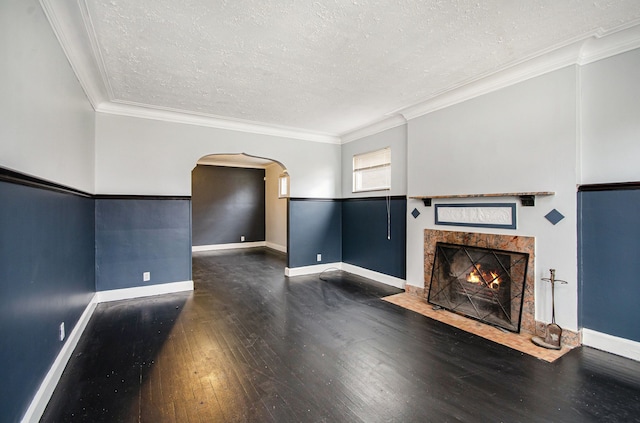 unfurnished living room with a tiled fireplace, dark hardwood / wood-style flooring, a textured ceiling, and ornamental molding