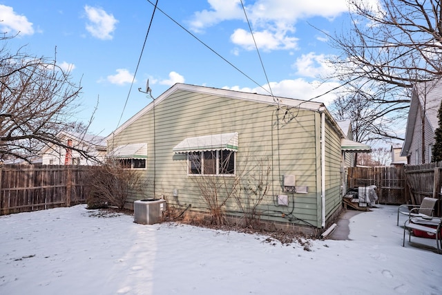 snow covered back of property featuring cooling unit