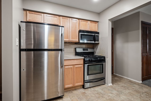 kitchen featuring stainless steel appliances, light brown cabinetry, and decorative backsplash