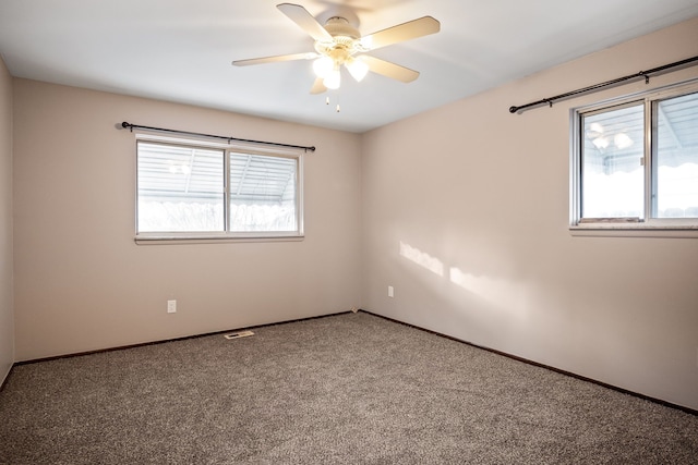 carpeted spare room featuring a wealth of natural light and ceiling fan