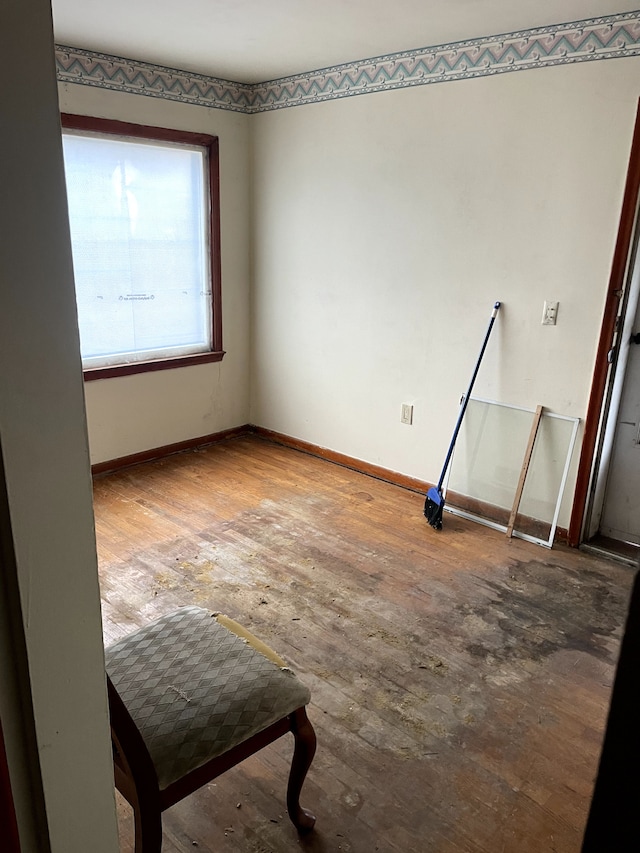 spare room with baseboards and wood-type flooring