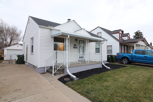 view of front of home with a front yard, a garage, an outdoor structure, and covered porch