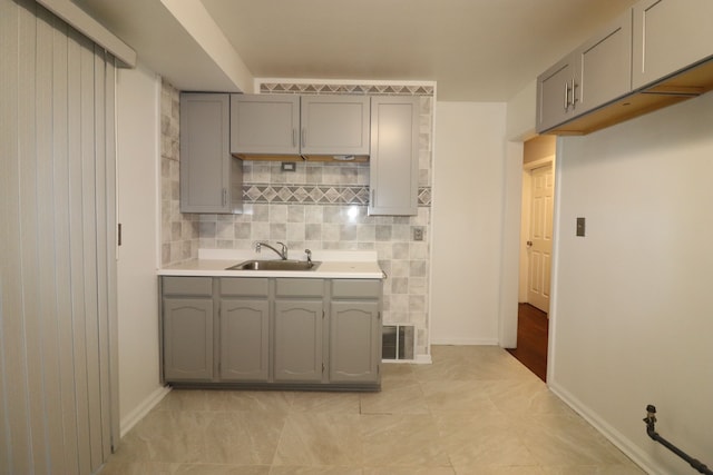 kitchen featuring gray cabinets, light tile patterned floors, sink, and tasteful backsplash