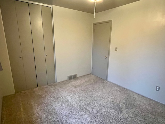 unfurnished bedroom with light carpet and a closet