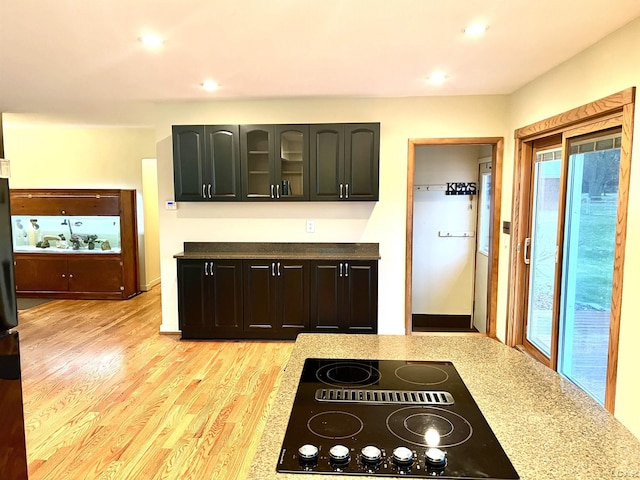 kitchen featuring dark brown cabinetry, light stone countertops, black electric stovetop, and light hardwood / wood-style floors