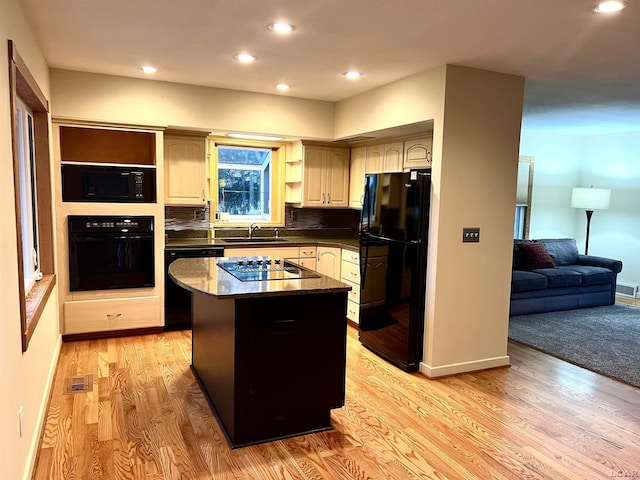 kitchen featuring backsplash, sink, black appliances, a center island, and light hardwood / wood-style floors