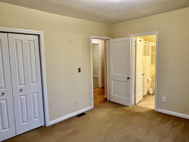 unfurnished bedroom featuring light carpet, connected bathroom, and a closet