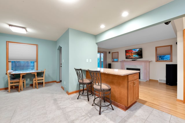 kitchen featuring a breakfast bar area, kitchen peninsula, and a high end fireplace