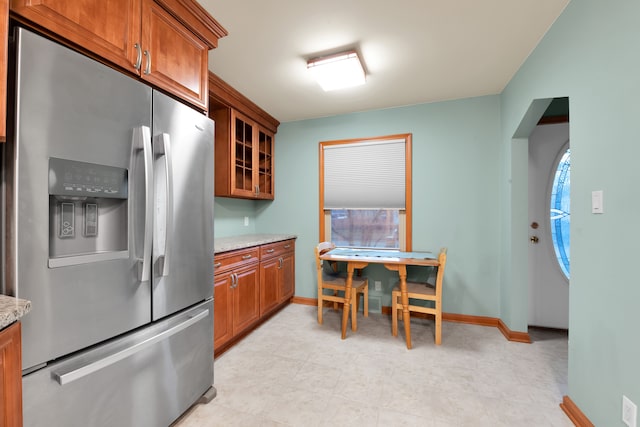 kitchen featuring light stone countertops and stainless steel fridge