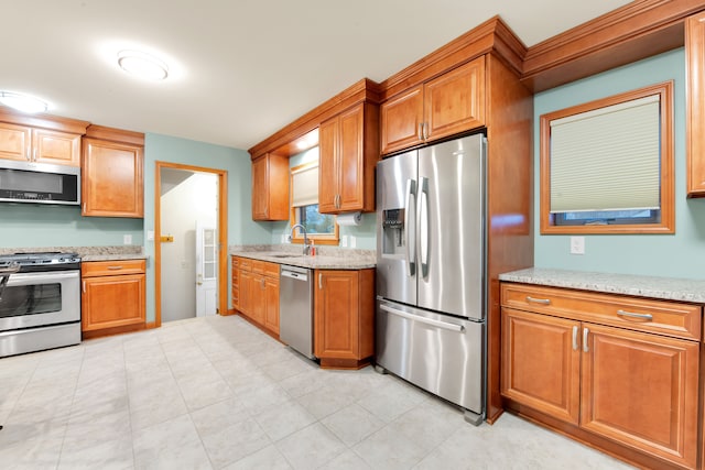 kitchen with light stone counters, sink, and stainless steel appliances