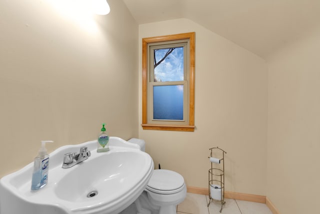 bathroom with toilet, tile patterned floors, vaulted ceiling, and sink