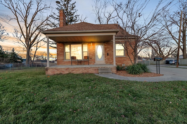 view of front of property with covered porch and a yard