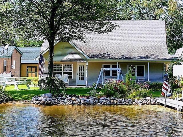 view of front of property with a front lawn, fence, covered porch, and a water view