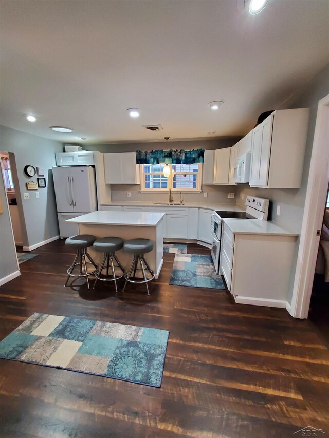 kitchen featuring a kitchen breakfast bar, white cabinetry, a kitchen island, and white appliances