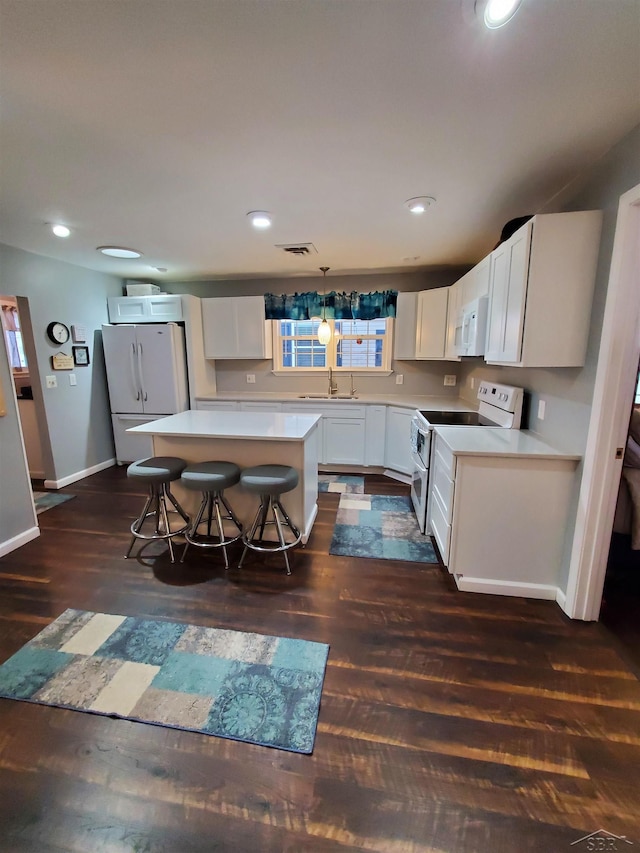 kitchen with white appliances, dark wood-style flooring, a center island, light countertops, and white cabinetry