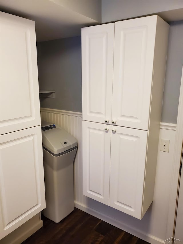 laundry room featuring dark wood-style flooring, wainscoting, and cabinet space