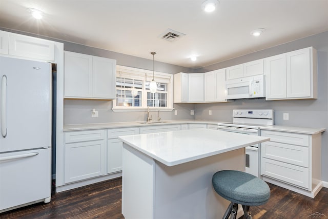 kitchen featuring white appliances, visible vents, dark wood finished floors, a sink, and a kitchen breakfast bar