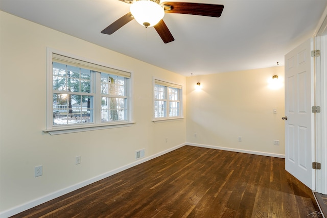 unfurnished room featuring visible vents, baseboards, dark wood-style floors, and a ceiling fan