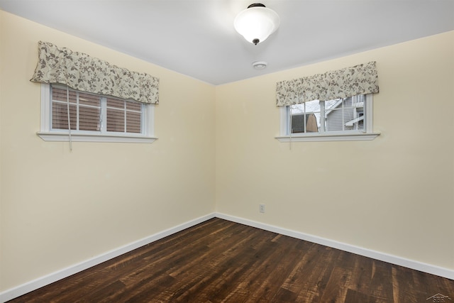 unfurnished room featuring baseboards and dark wood-style flooring