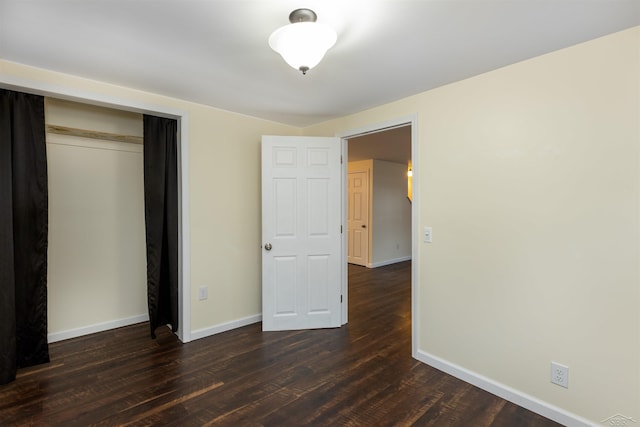 unfurnished bedroom featuring a closet, baseboards, and dark wood-style floors