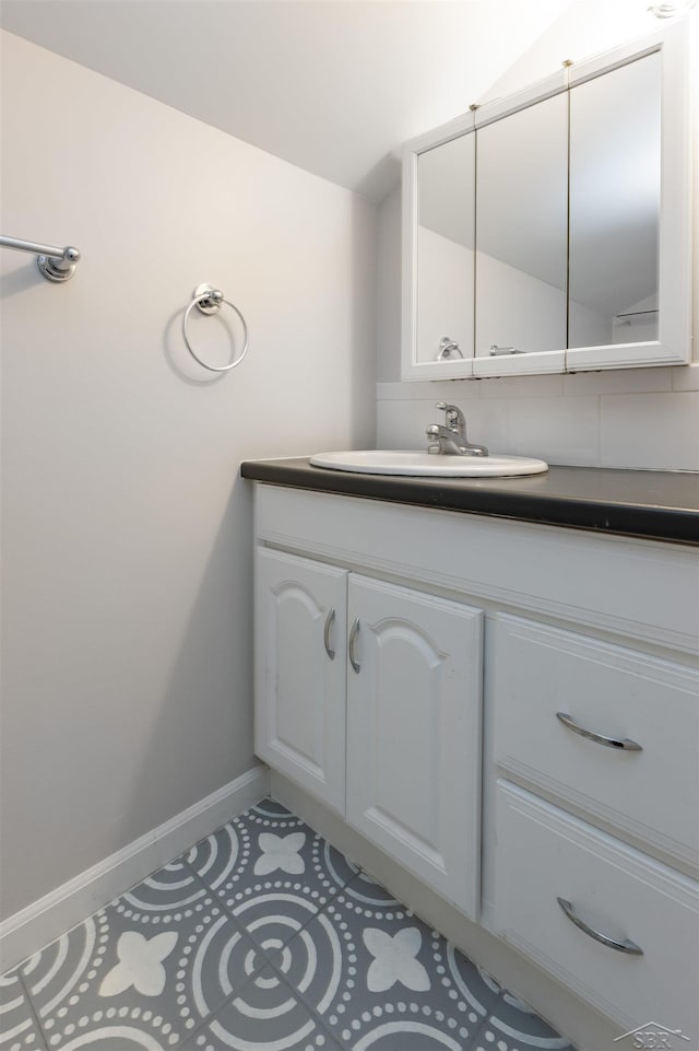 bathroom with baseboards, lofted ceiling, and vanity