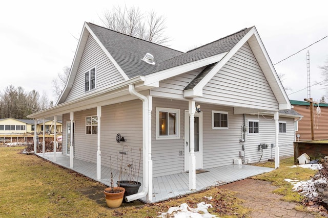 view of side of home featuring a yard and roof with shingles