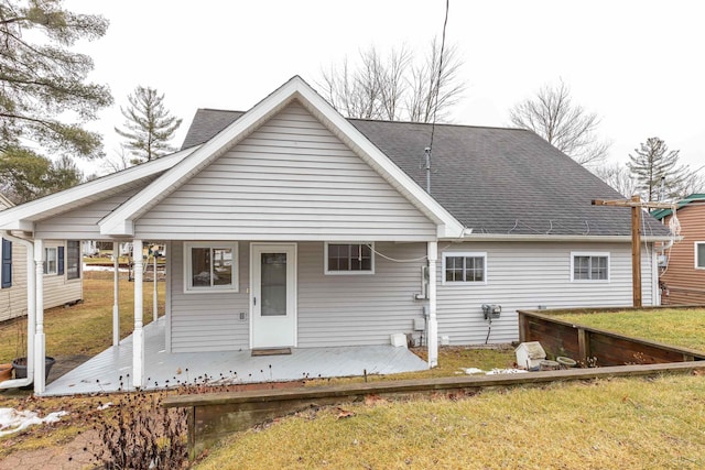 rear view of property with a lawn and roof with shingles