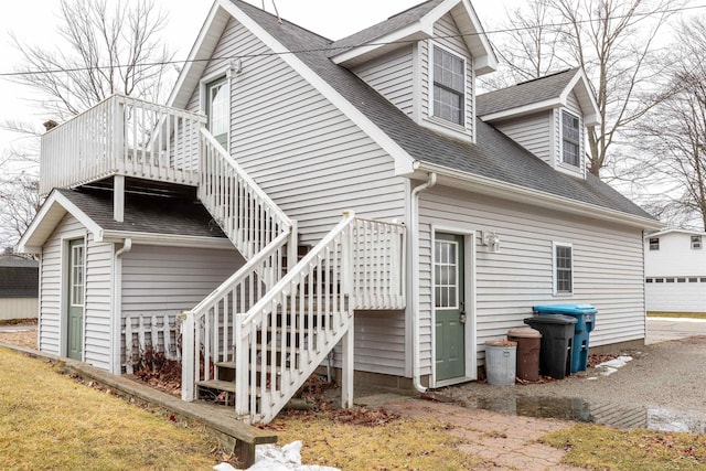 back of property with stairway and a shingled roof