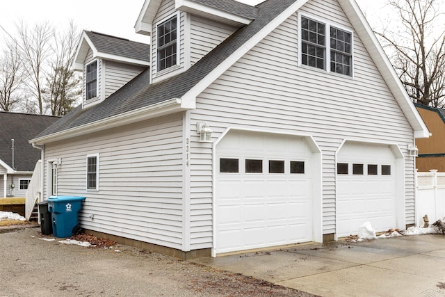 view of side of property featuring an attached garage and roof with shingles