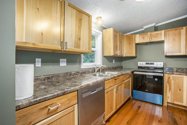 kitchen with sink, dark stone countertops, ornamental molding, a textured ceiling, and appliances with stainless steel finishes